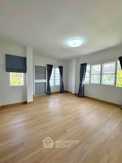 Spacious empty room with large windows and wooden flooring, perfect for customization.