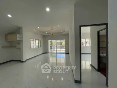 Spacious modern living room with glossy floors and large windows offering natural light.