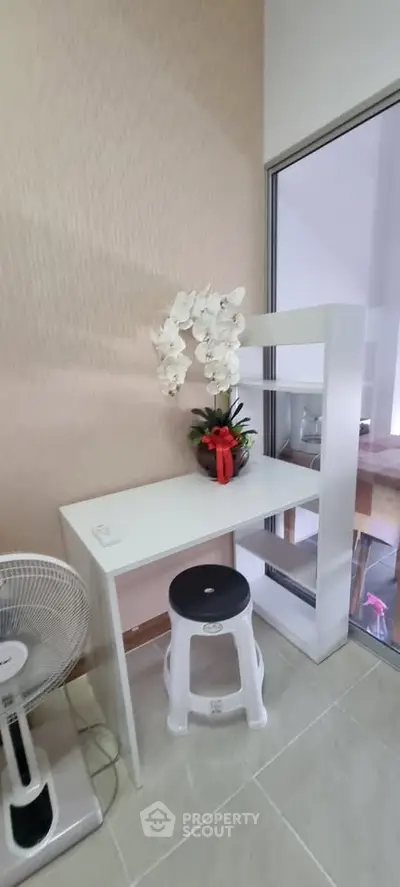 Modern study nook with white desk, stool, and decorative plant in a bright interior space.