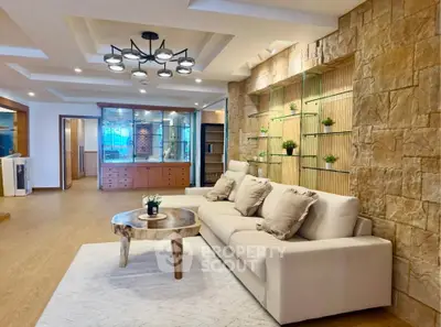Luxurious living room with modern decor and stone accent wall, featuring a plush sofa and stylish lighting.