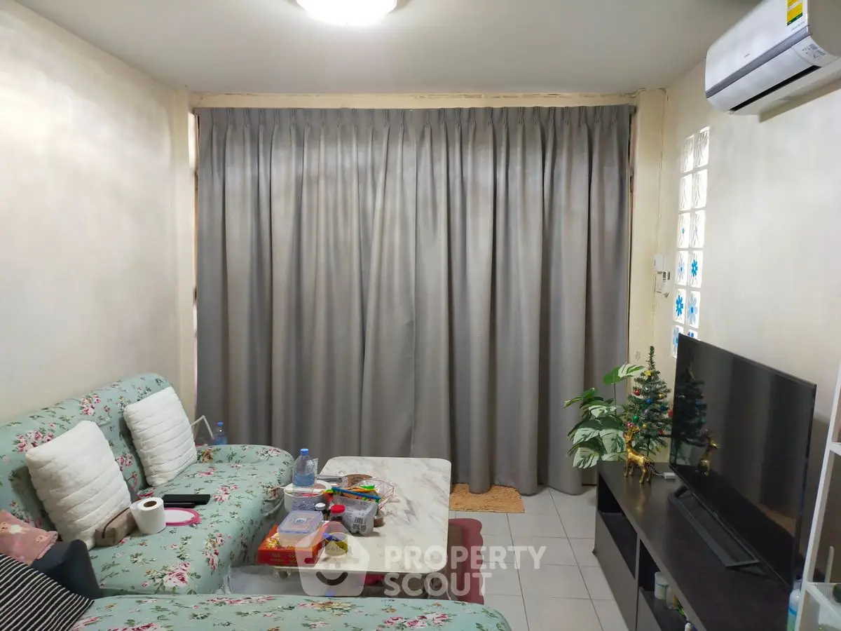 Cozy living room with floral sofa, TV, and air conditioning, perfect for relaxation.