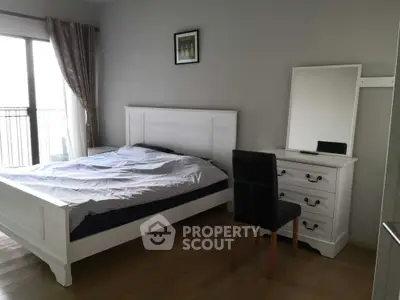 Spacious bedroom with elegant white furniture and natural light from large window.