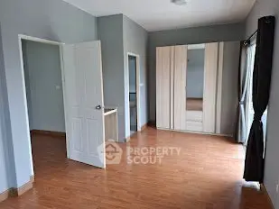 Spacious bedroom with wooden flooring and large wardrobe, perfect for modern living.