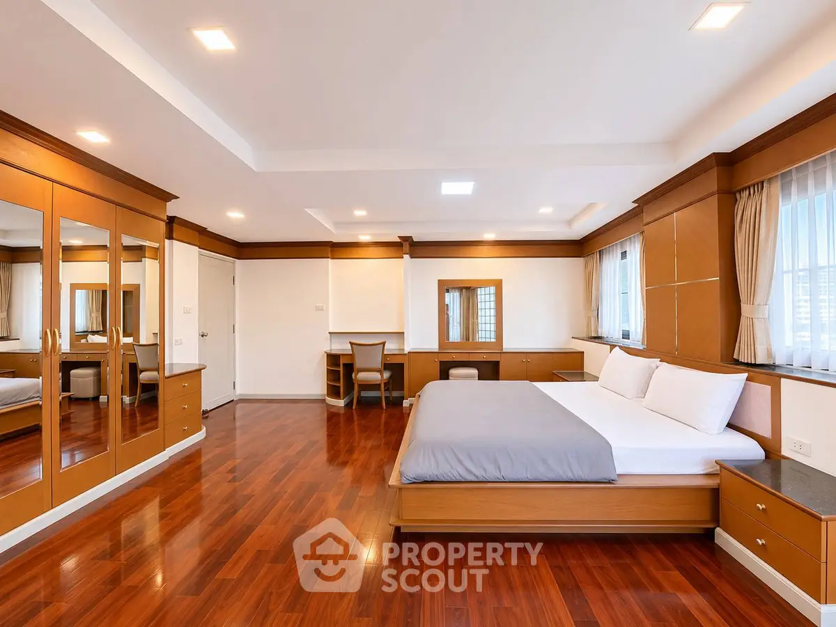 Spacious bedroom with elegant wooden flooring and built-in wardrobes