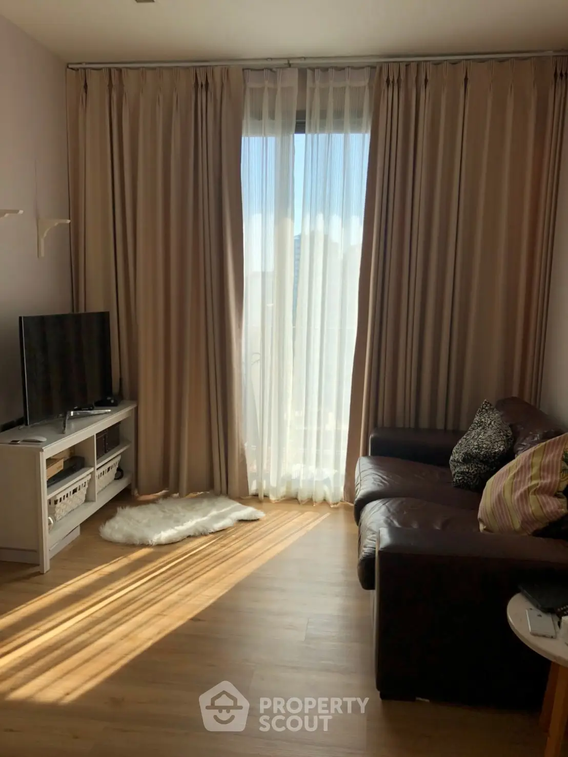 Cozy living room with leather sofa and natural light through large window.