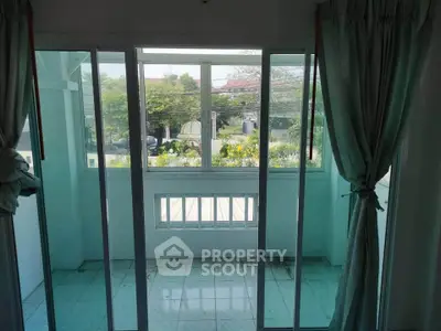 Bright balcony with sliding glass doors and garden view, perfect for relaxation.