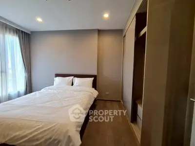Modern bedroom with cozy bed and ample natural light in a stylish apartment.