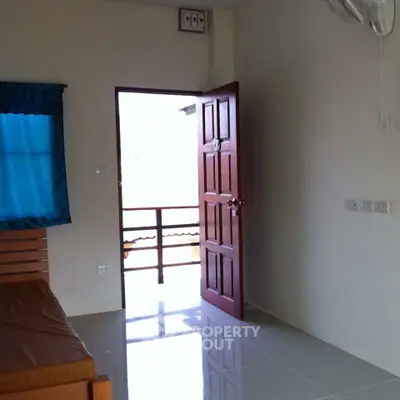 Bright and airy bedroom with glossy tiled flooring, a large window allowing natural light, and an air conditioning unit for comfort.