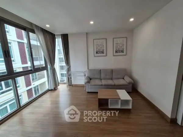 Spacious living room with large windows and modern decor in a high-rise apartment.