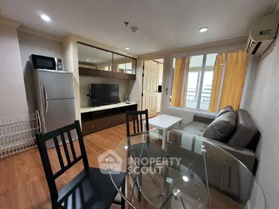 Modern living room with glass dining table, cozy sofa, and sleek kitchen appliances in a stylish apartment.