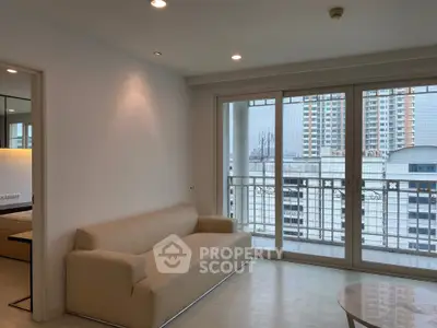 Modern living room with large windows and city view, featuring a beige sofa and sleek design.