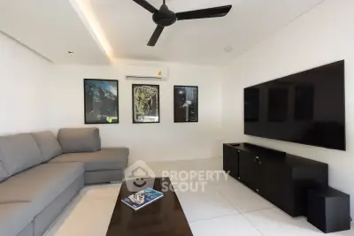 Modern living room with sleek design, featuring a large TV, stylish sofa, and contemporary decor.