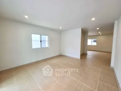 Spacious open-plan living area with tiled flooring and ample natural light.