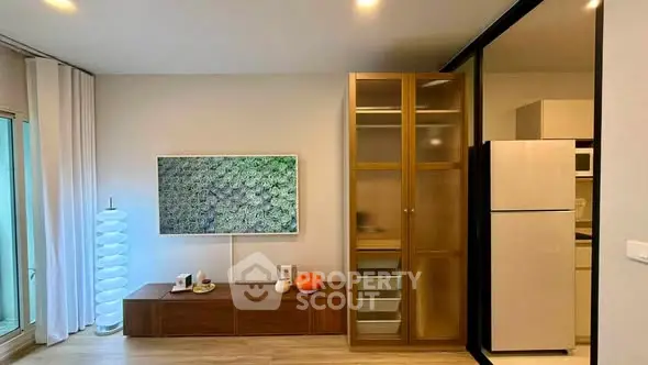 Modern living room with stylish decor and large cabinet, featuring a sleek refrigerator and elegant lighting.