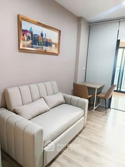 Cozy living room with modern sofa and dining area, featuring a scenic wall art and balcony access.
