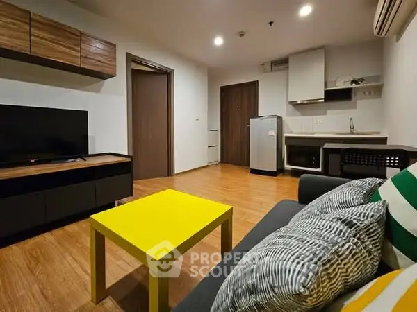 Modern living room with vibrant yellow table and sleek kitchen area