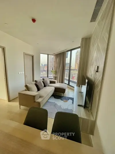 Modern living room with stylish decor and city view, featuring a cozy sofa and wall-mounted TV.