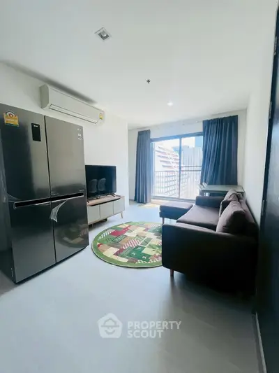 Modern living room with large fridge, cozy sofa, and city view balcony.
