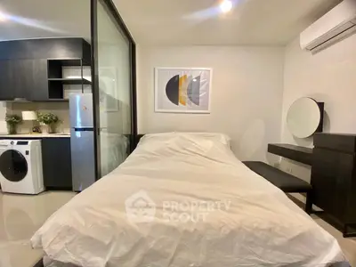 Modern studio apartment with sleek kitchen and cozy bedroom area, featuring a washing machine and stylish decor.