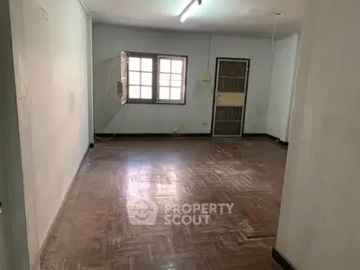 Spacious empty room with wooden flooring and natural light, ideal for customization.
