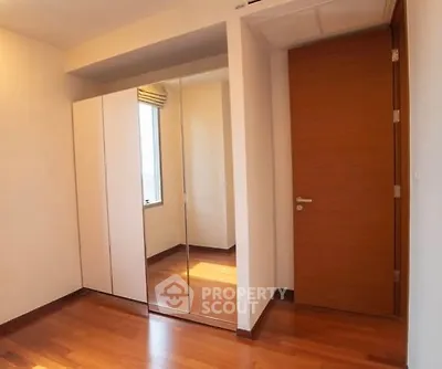 Spacious bedroom with wooden flooring and mirrored wardrobe doors