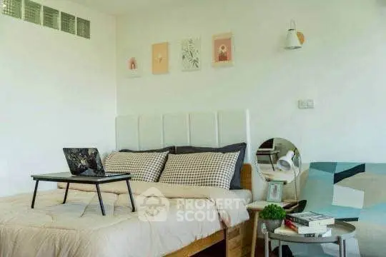 Cozy bedroom with modern decor and laptop on bed, perfect for relaxation and work-from-home setup.