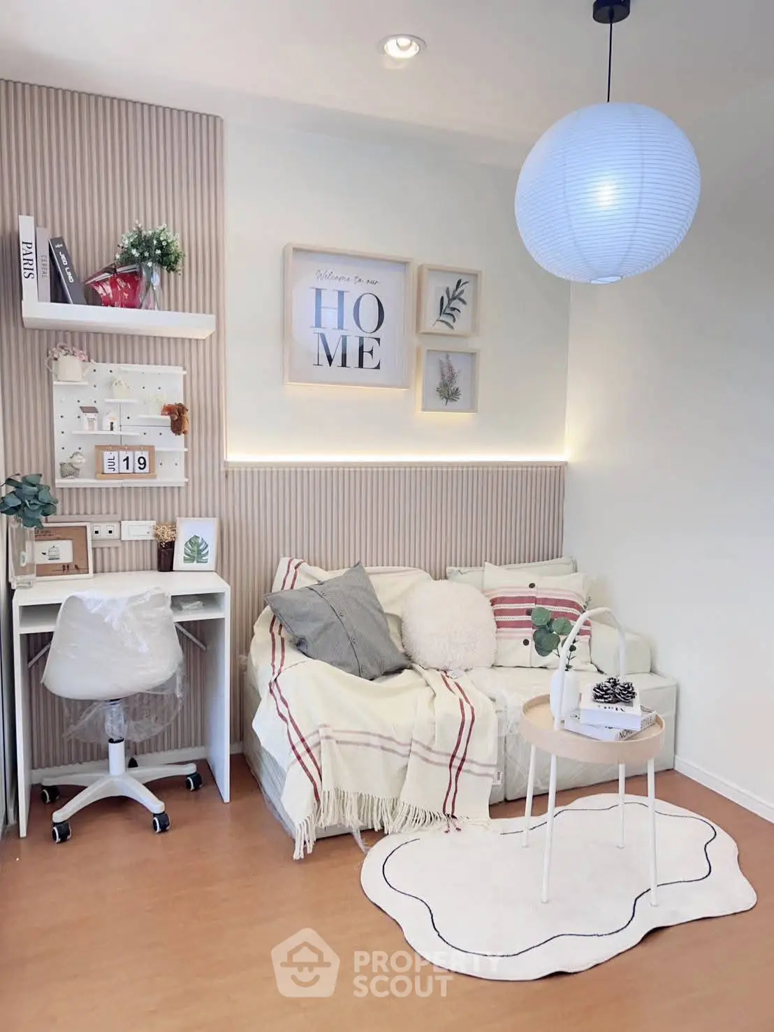 Charming living room with cozy decor, featuring a stylish sofa, modern desk, and elegant wall art.