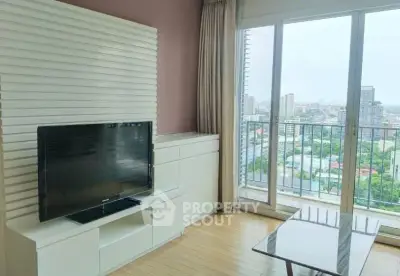 Modern living room with large TV and stunning city view from balcony.