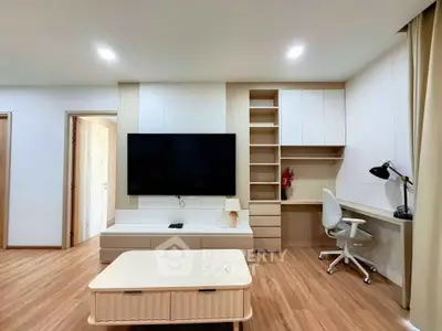 Modern living room with sleek TV setup and stylish workspace, featuring wooden flooring and contemporary furniture.