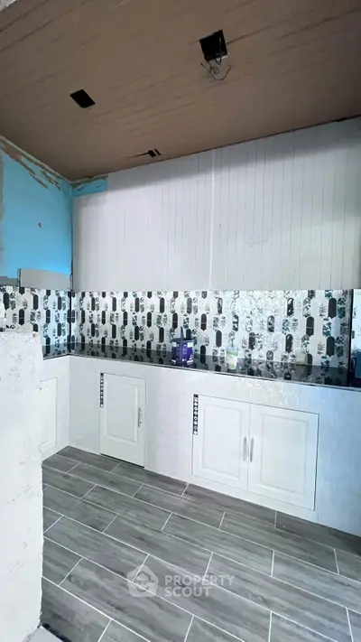 Modern kitchen under renovation with stylish backsplash and tiled flooring.