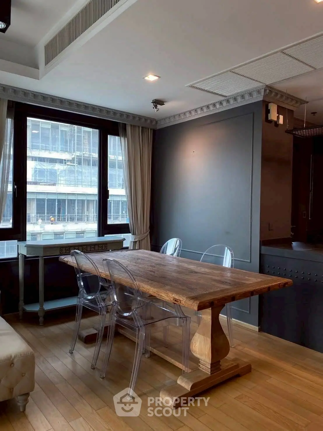 Stylish dining area with wooden table and modern chairs in a high-rise apartment.
