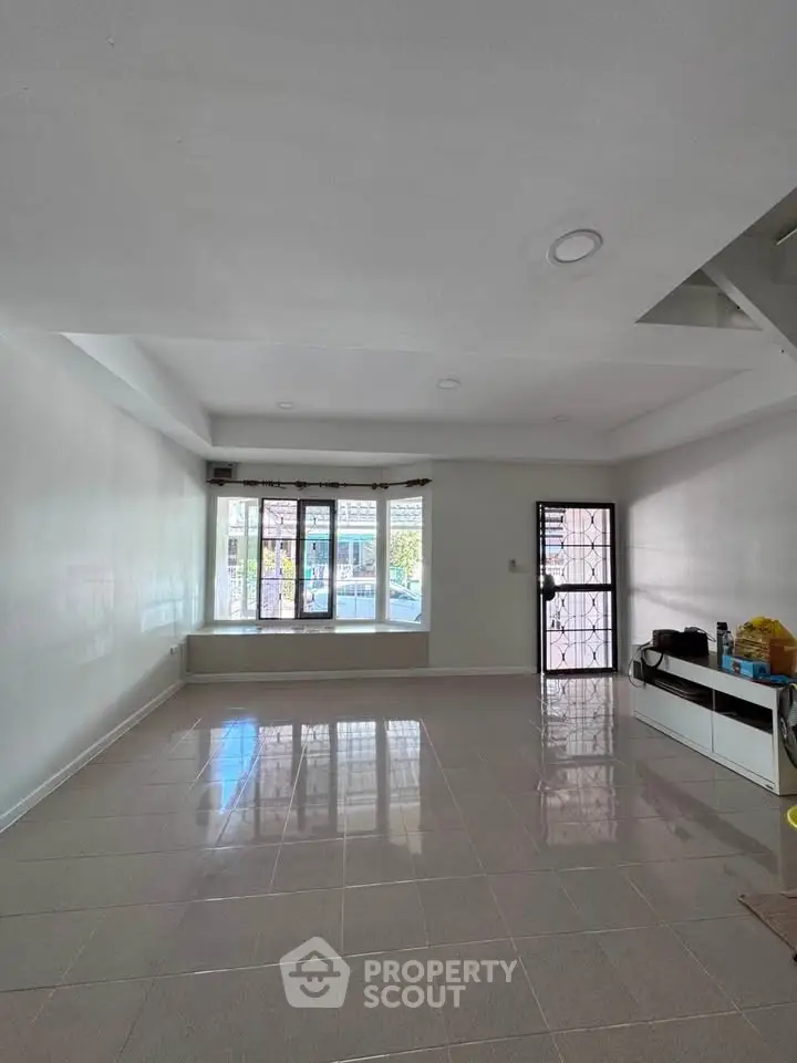 Spacious living room with large windows and tiled flooring, perfect for natural light.