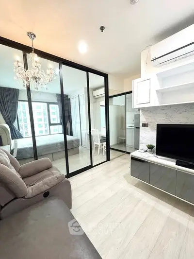 Modern living room with glass partitions, elegant chandelier, and cozy seating area.