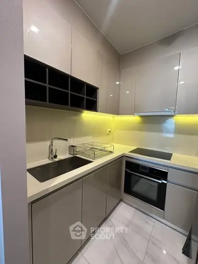 Modern kitchen with sleek cabinetry and built-in oven, featuring under-cabinet lighting.
