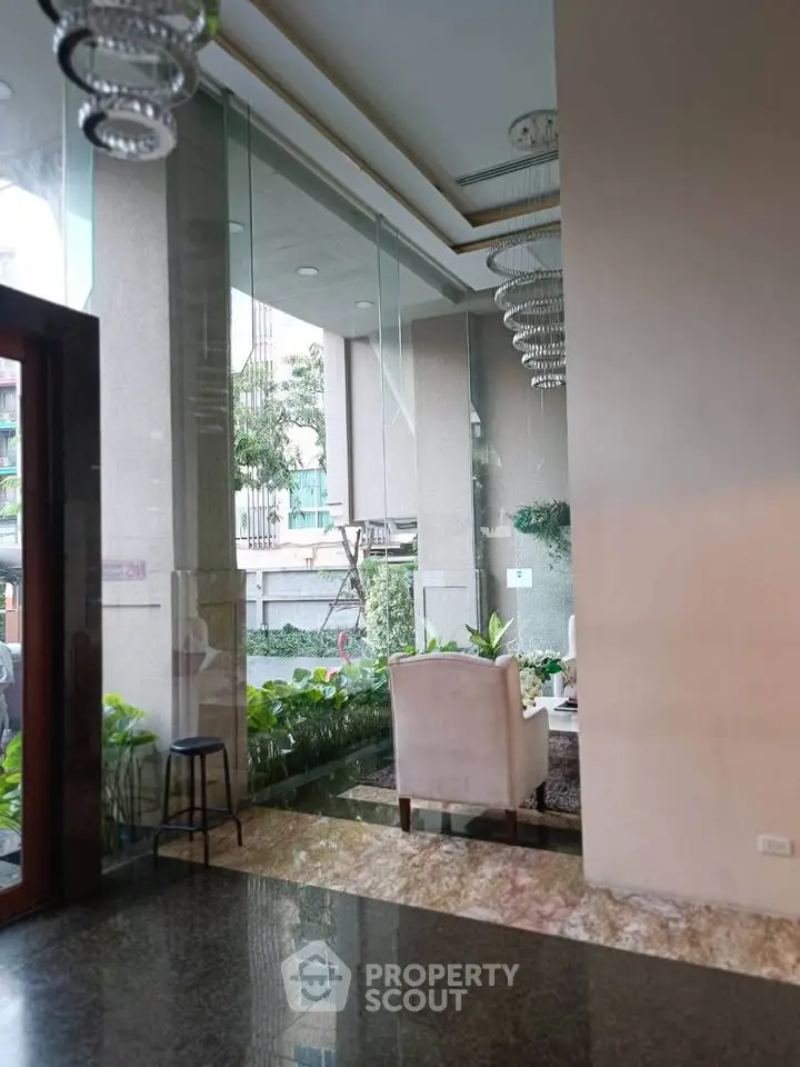 Luxurious building entrance with elegant seating and lush greenery, perfect for welcoming guests.