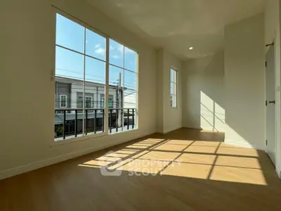 Bright and spacious room with large windows and wooden flooring, perfect for modern living.