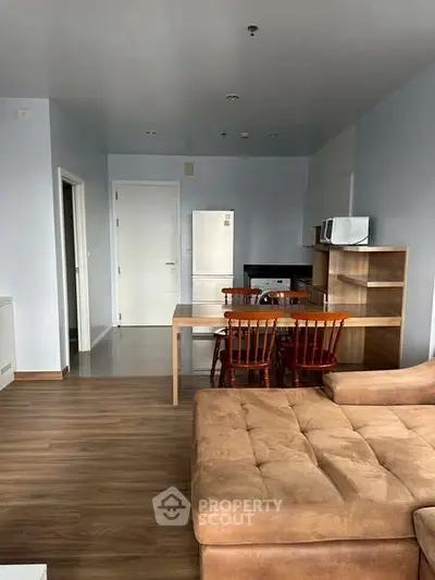 Modern living room with dining area and kitchen featuring wooden flooring and contemporary furniture.