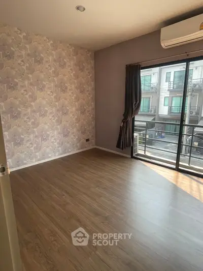 Spacious bedroom with elegant wallpaper and balcony access in modern apartment