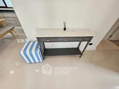 Modern interior with stylish console table and striped ottoman in bright living space.
