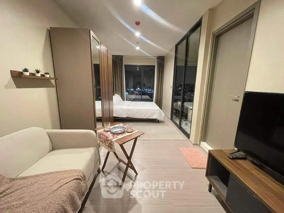 Modern studio apartment with cozy living area and bedroom, featuring large windows and stylish decor.