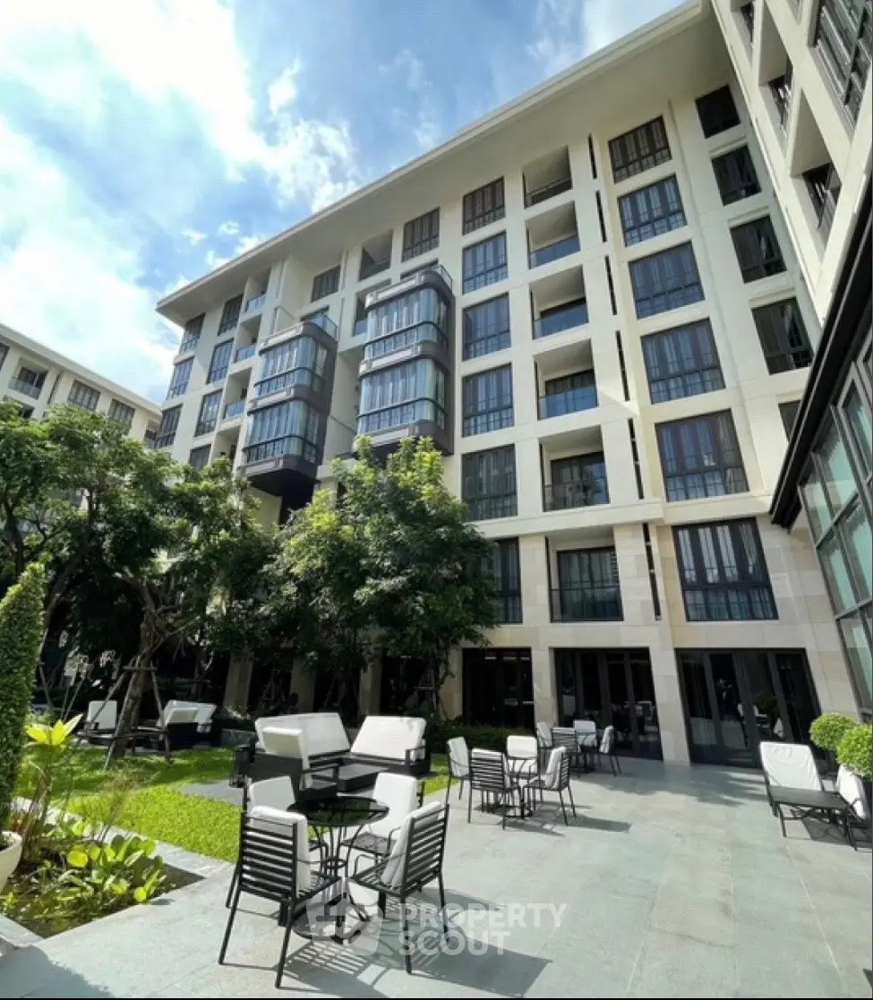 Modern apartment building with outdoor seating and lush greenery
