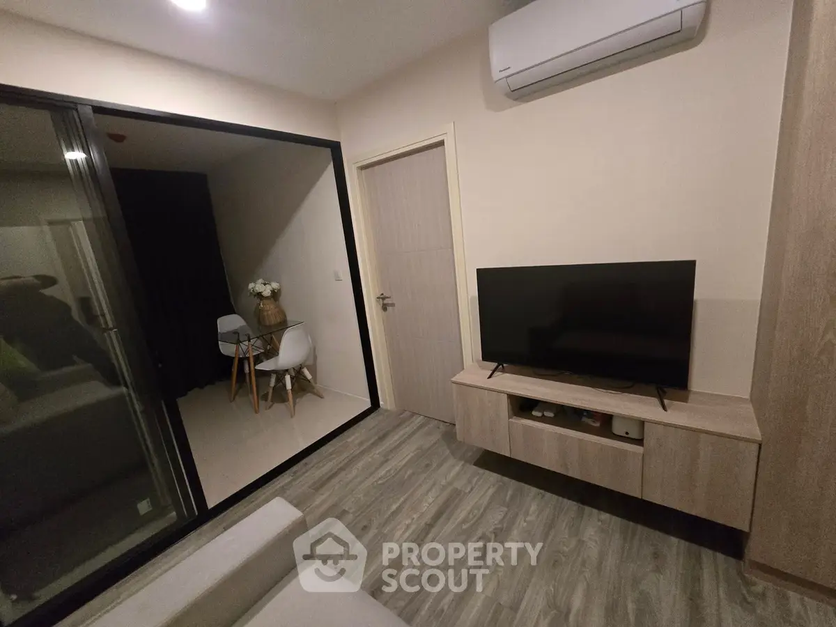 Modern living room with sleek TV setup and cozy dining nook, featuring stylish flooring and air conditioning.