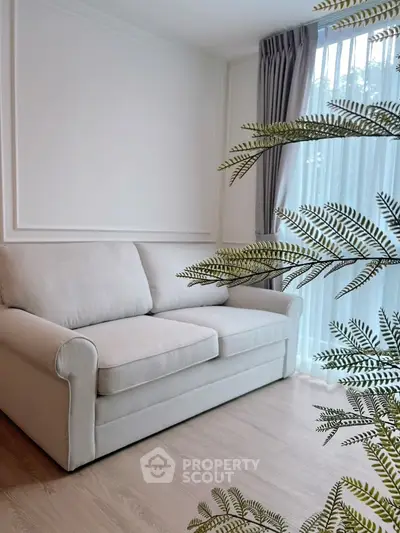 Cozy living room with elegant sofa and natural light through sheer curtains.