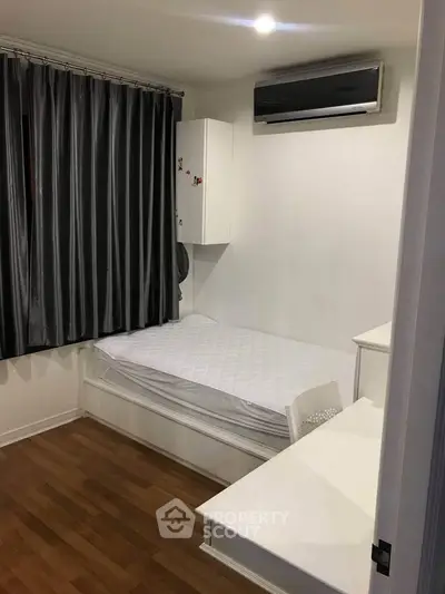 Cozy bedroom with single bed, study desk, and air conditioning in modern apartment.