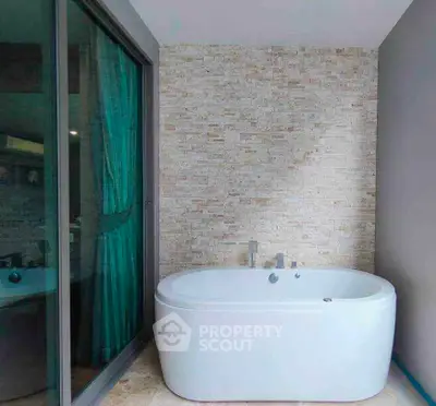 Luxurious bathroom with modern freestanding bathtub and elegant stone wall accent.