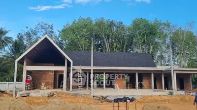 Modern house under construction with exposed brick and pitched roof in lush setting