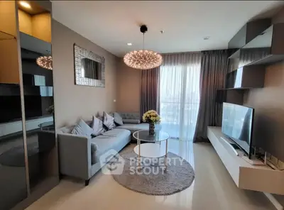 Modern living room with elegant decor, stylish chandelier, and large TV, perfect for relaxation.