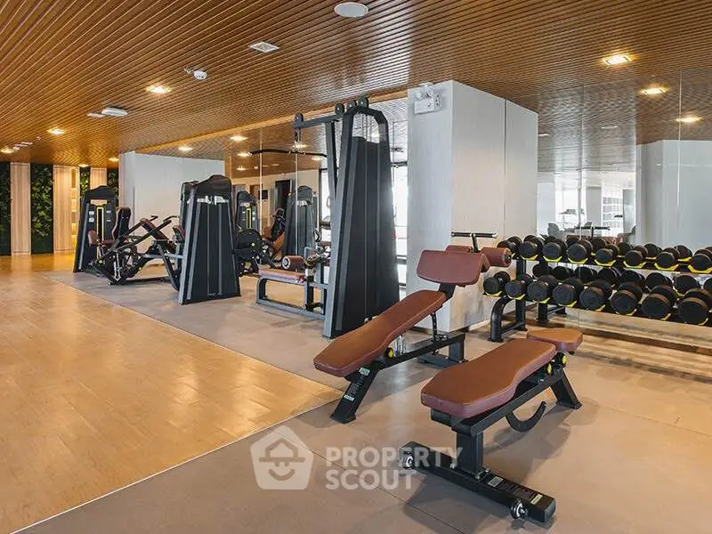 Modern gym with state-of-the-art equipment and wooden ceiling design in luxury residential building.