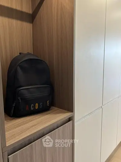 Modern storage area with sleek wooden cabinetry and stylish backpack display.