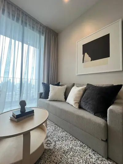 Modern living room with stylish sofa and abstract art, featuring floor-to-ceiling windows and cozy decor.